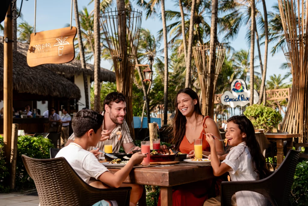 a imagem mostra uma família sorrindo e almoçando na Vila Azul do Mar nas férias do Beach Park