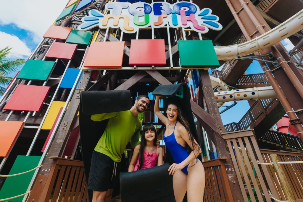 a imagem mostra uma família em frente a uma das atrações do Aqua Park, aproveitando as férias no Beach Park, perto de Fortaleza