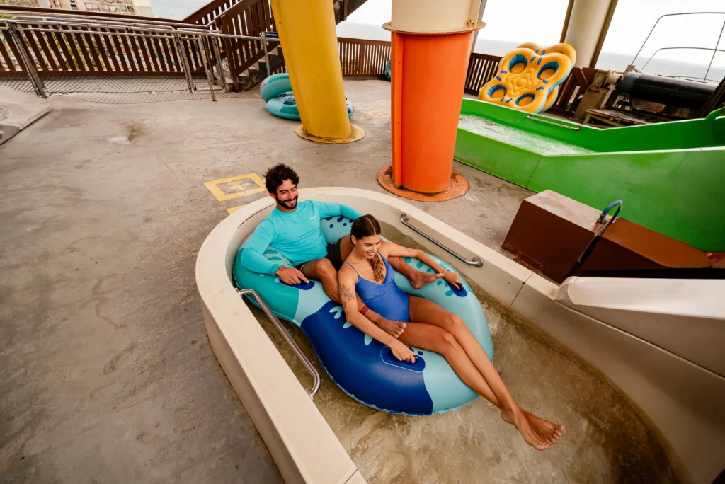 a imagem mostra um casal em uma boia dupla prestes a curtir uma das atrações do Aqua Park com a promoção Residentes do Ceará no Beach Park