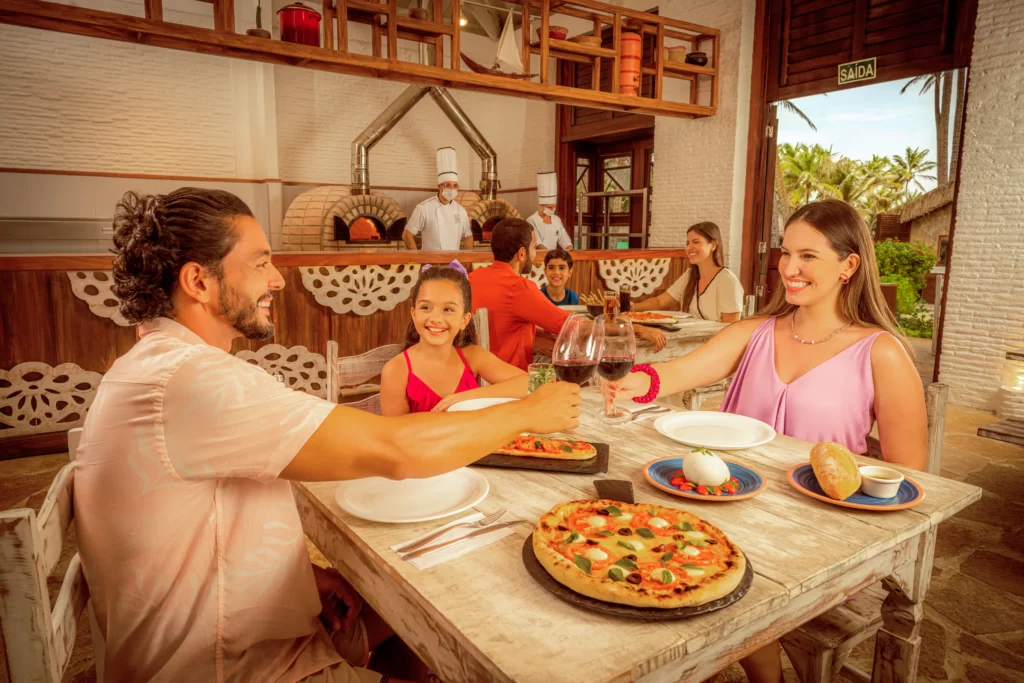 a imagem mostra uma família saboreando uma pizza na pizzaria da Vila Azul do Mar para curtir o feriado no Beach Park