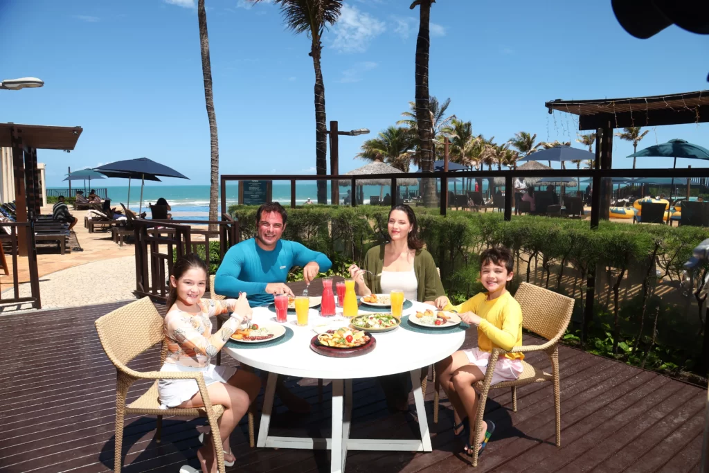 a imagem mostra uma família aproveitando as férias no ceará com os sabores da gastronomia regional com vista privilegiada para o mar nos resorts pé na areia do beach park