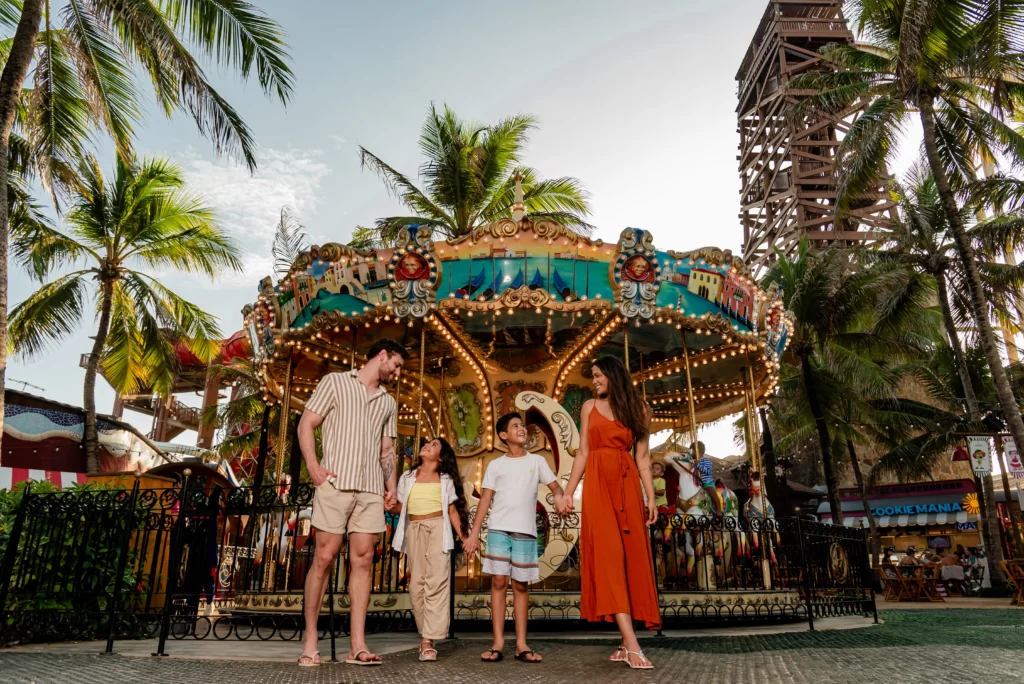 a imagem mostra uma família feliz em frente ao carrossel da vila azul do mar, no beach park